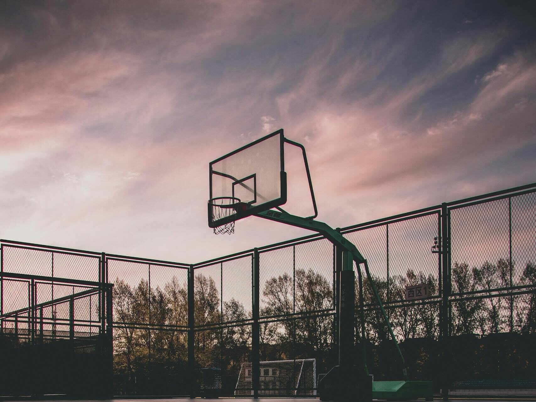 A tranquil view of a basketball court with reflections during sunset, creating a serene urban landscape.